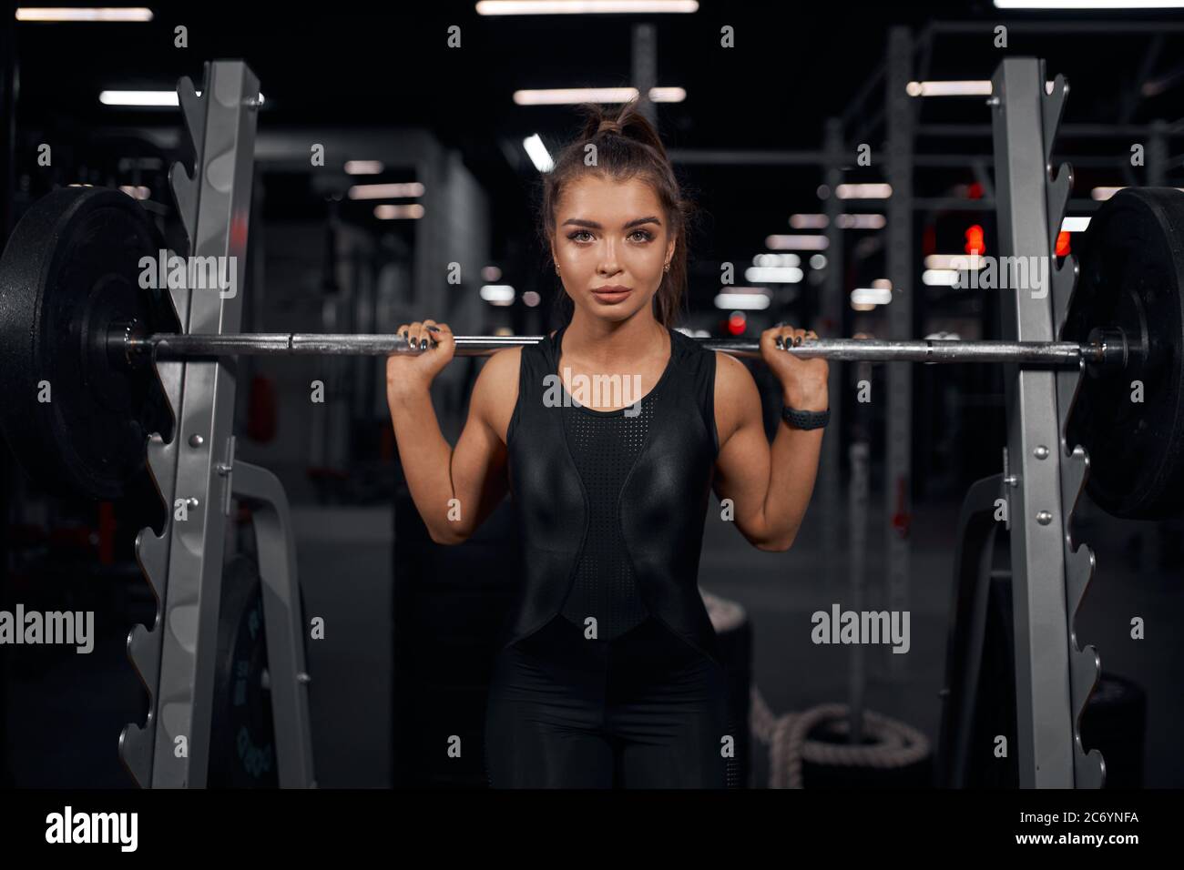 Portrait of charming active powerlifter taking photo with heavy
