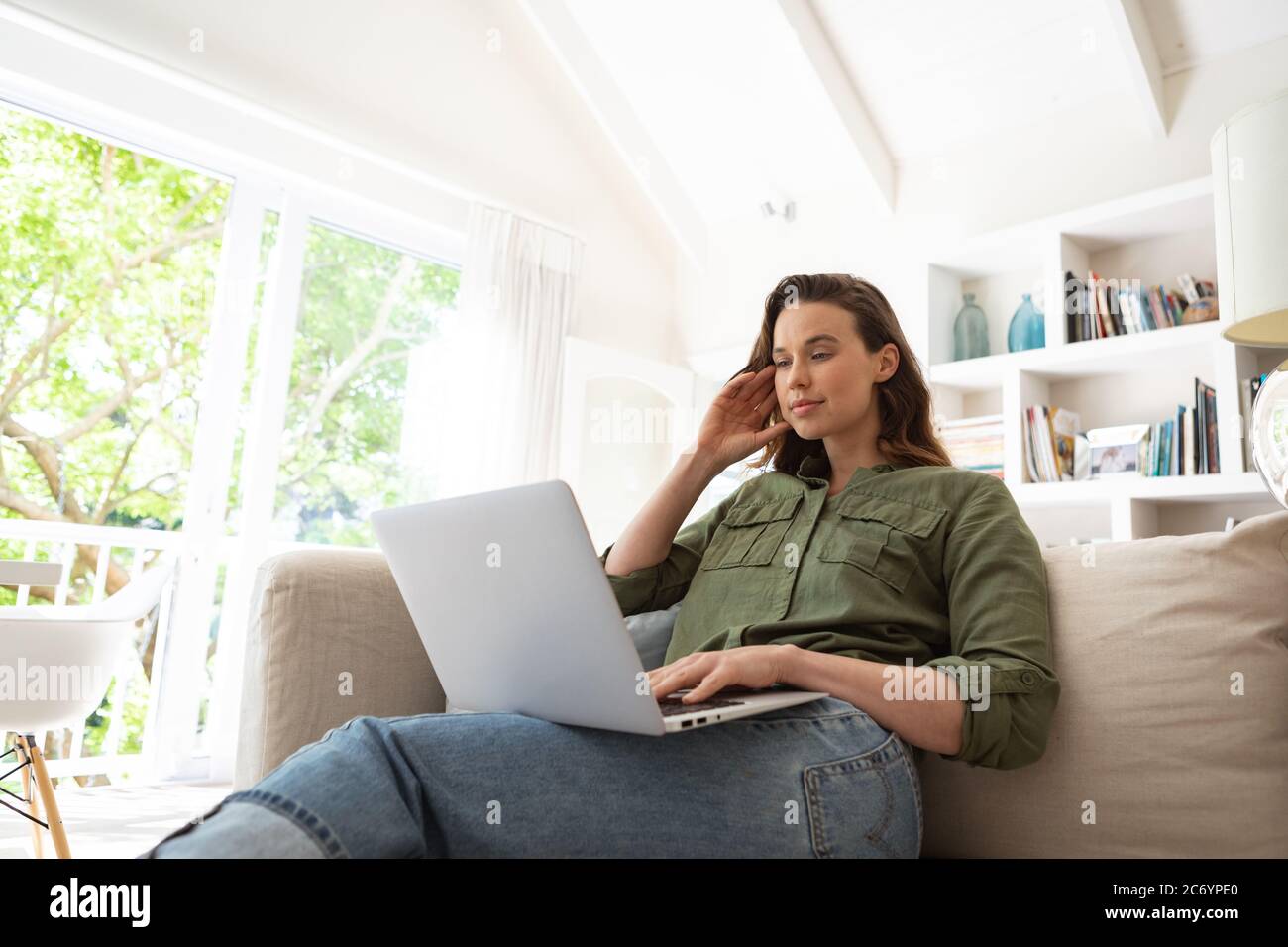 Woman using laptop while sitting on couch at home Stock Photo - Alamy