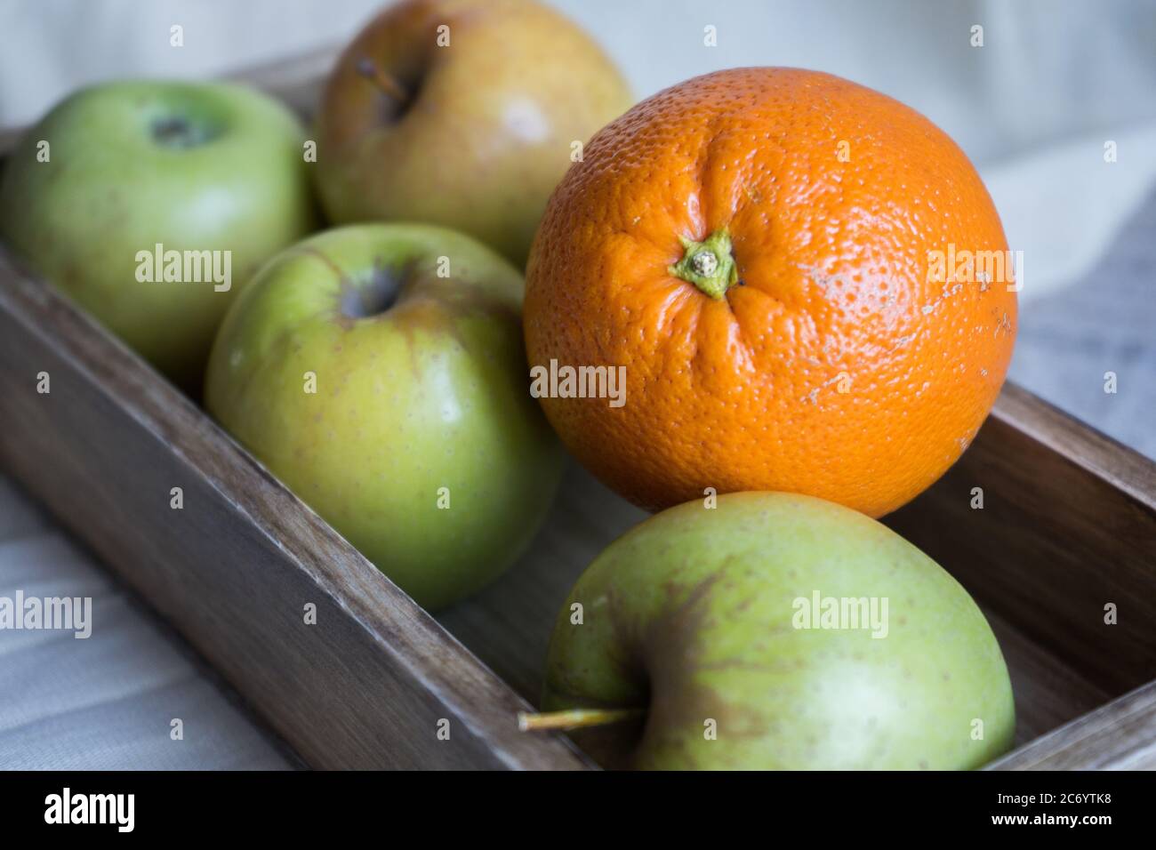 still life with apples and orange in a wooden box on a background of ...