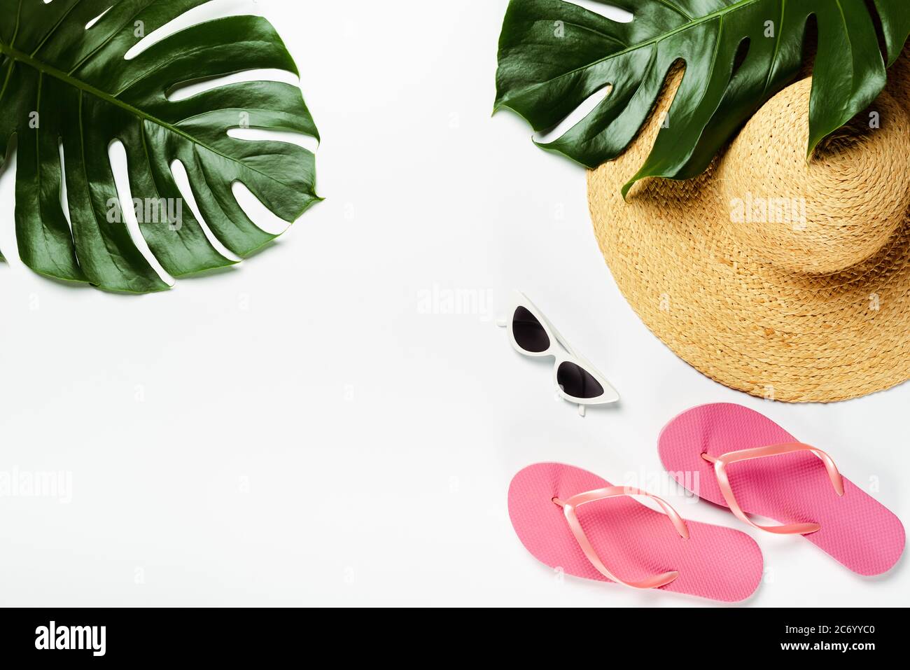 top view of green palm leaves, straw hat, sunglasses and flip flops on ...