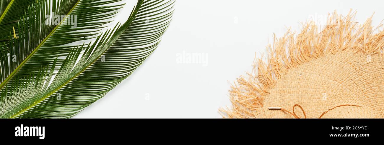 top view of green palm leaves near straw hat on white background ...