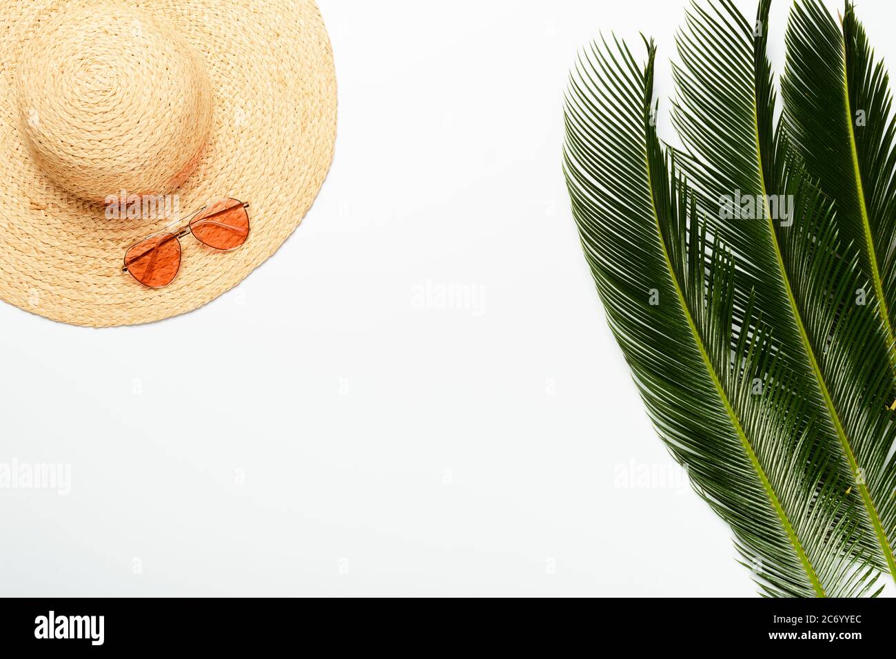 top view of green palm leaves near straw hat and sunglasses on white ...
