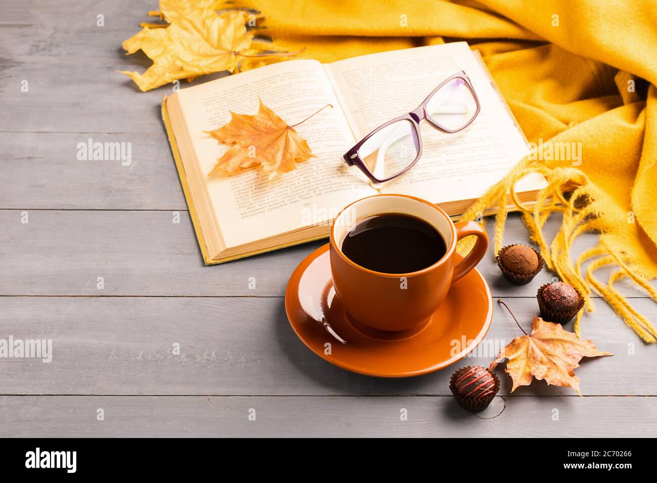 Hot drink coffee or tea in a cup open book glasses on autumn