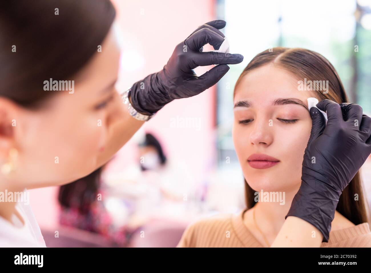 Brow artist clean face with sponge professional of young woman Stock