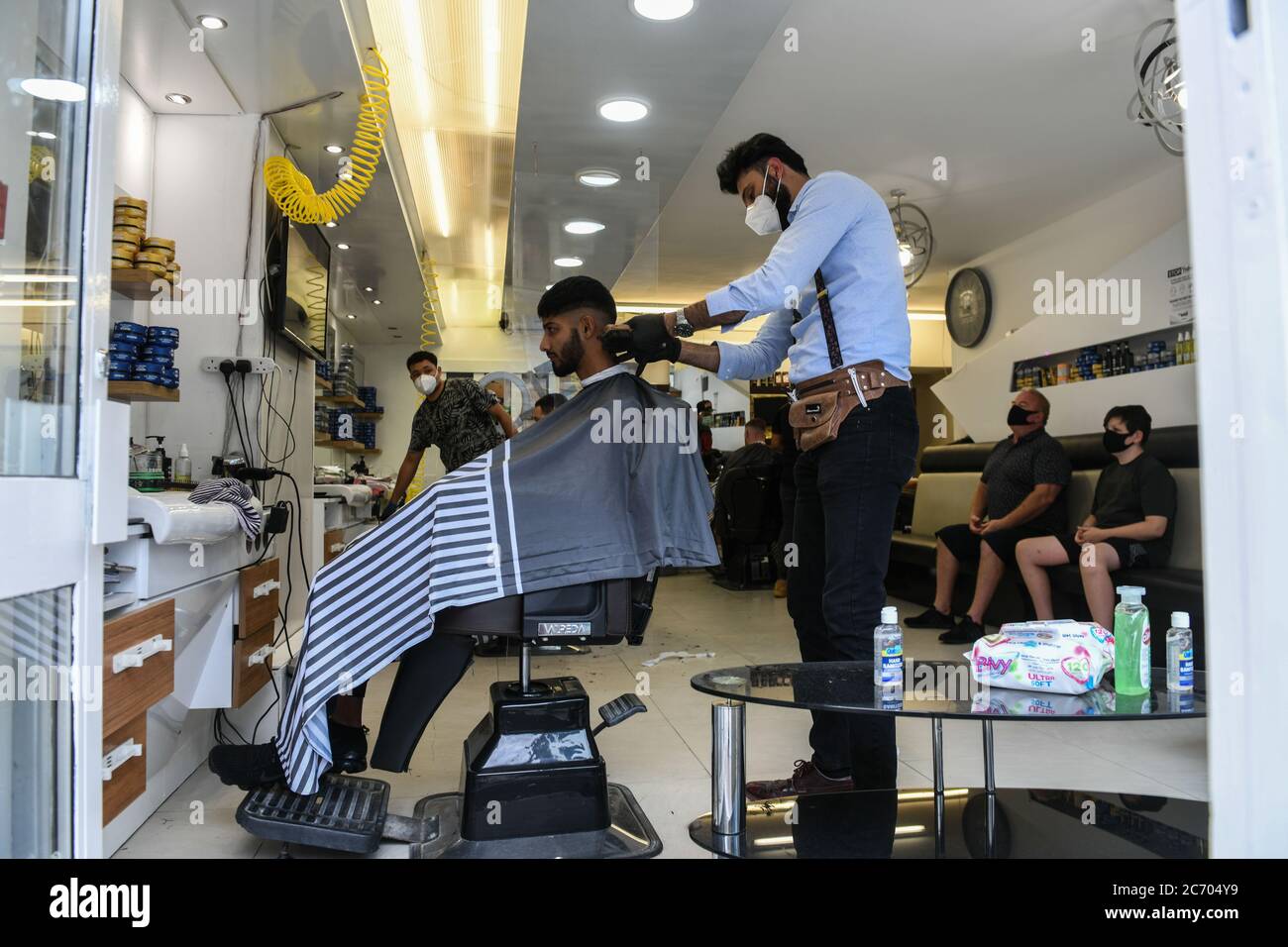 Swansea, Wales, UK. 13th July 2020.Credit :Business owner, AK Zadah cuts a  customers hair in his barbers, Figaro's, in Swansea as hairdressers across  Wales open for business for the first time since