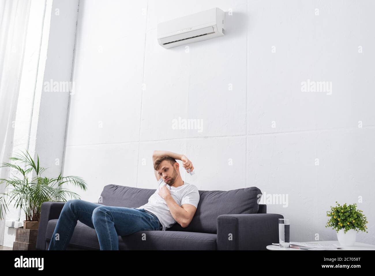 sad man feeling with broken air conditioner at home during summer heat Stock Photo