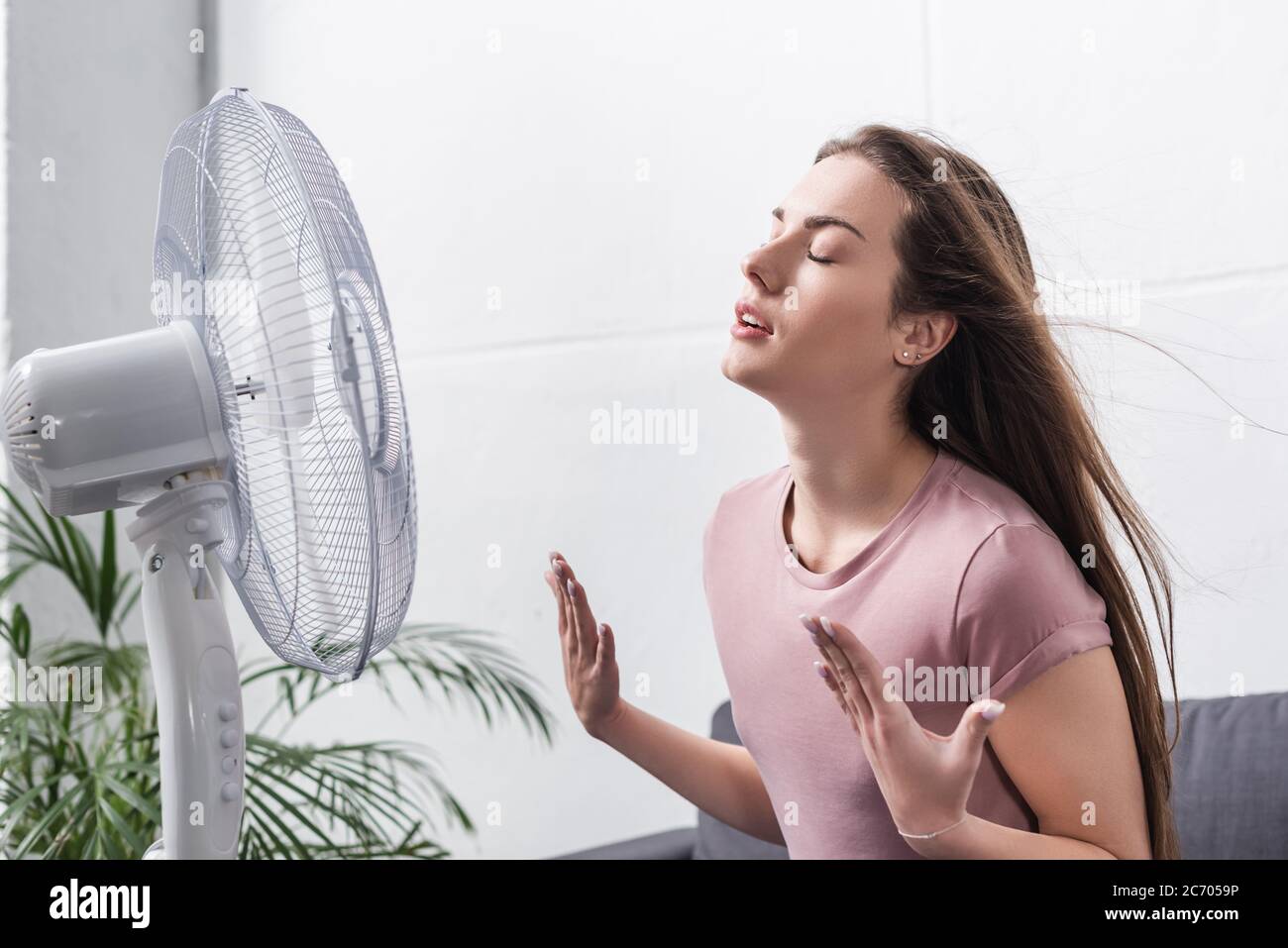 beautiful girl feeling comfortable with electric fan during summer heat ...