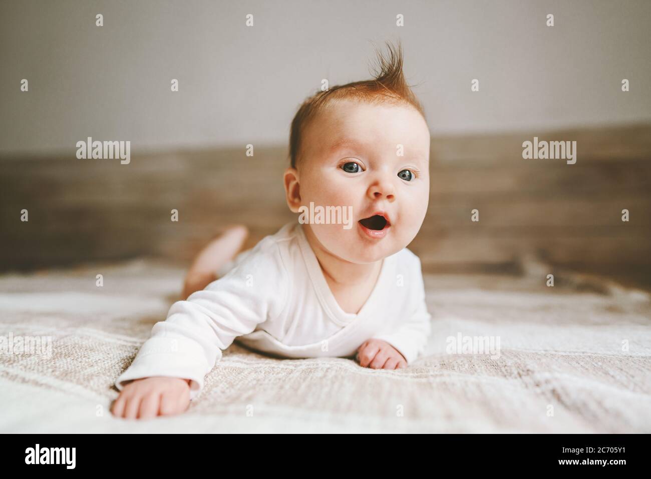 Cute baby infant crawling at home curious child portrait family lifestyle 3 month old girl kid Stock Photo