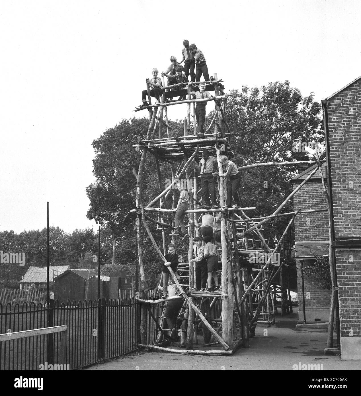 1960s, historical, a group of schoolboys on a tall hand-built wooden climbing frame in an outdoor area at an inner London boys state boarding school, South East London, with a number of them high-up at the top of the structure. Attached to a wall of a building, it is not a typical playground climbing frame and in the days when there was not the health and safety rules and regulations, great fun for the young boys and providing a sense of adventure and exercise in a city environment. Stock Photo