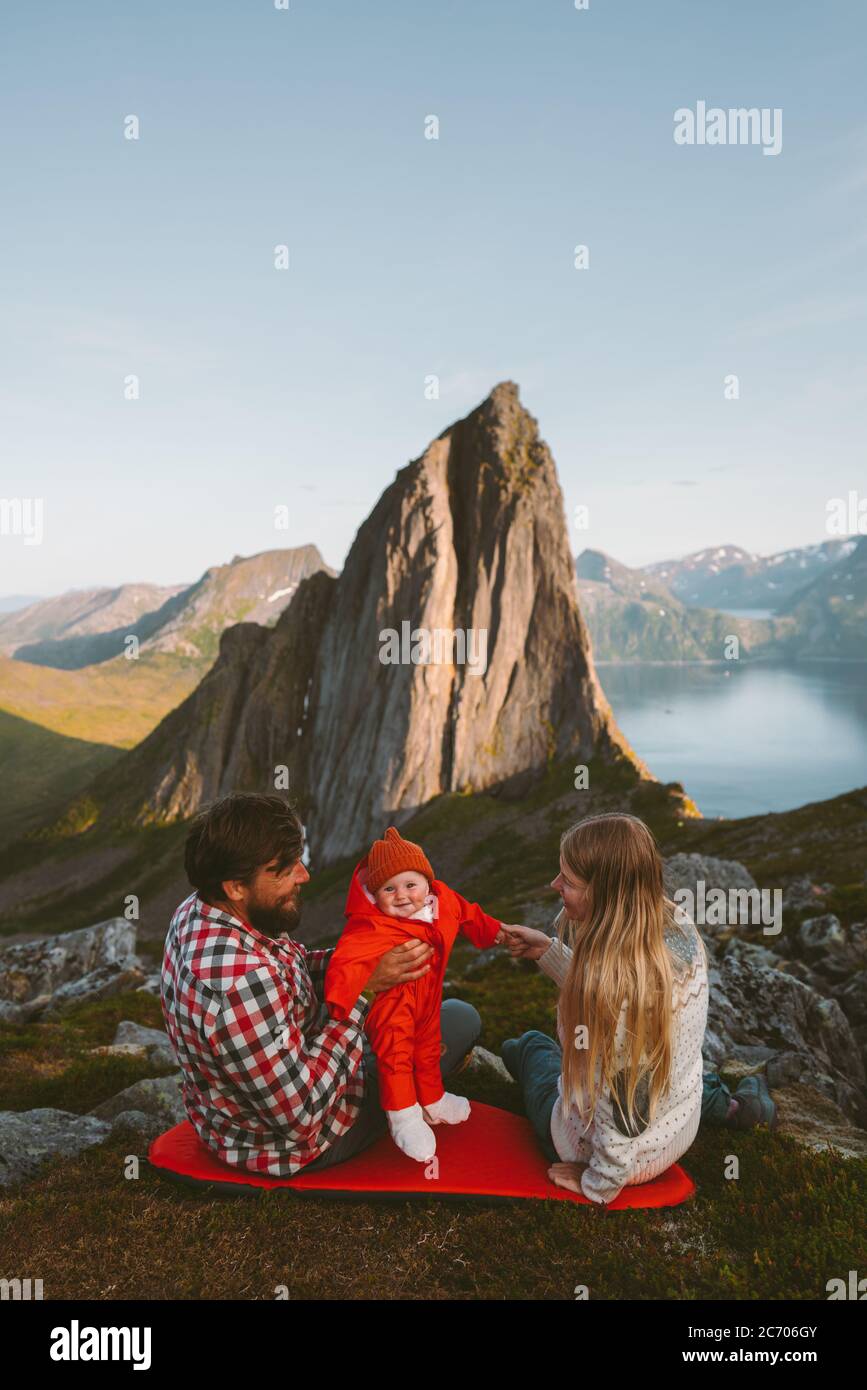 Family vacation with baby couple mother and father parents traveling with child camping outdoors healthy lifestyle tour in Norway Segla mountain view Stock Photo