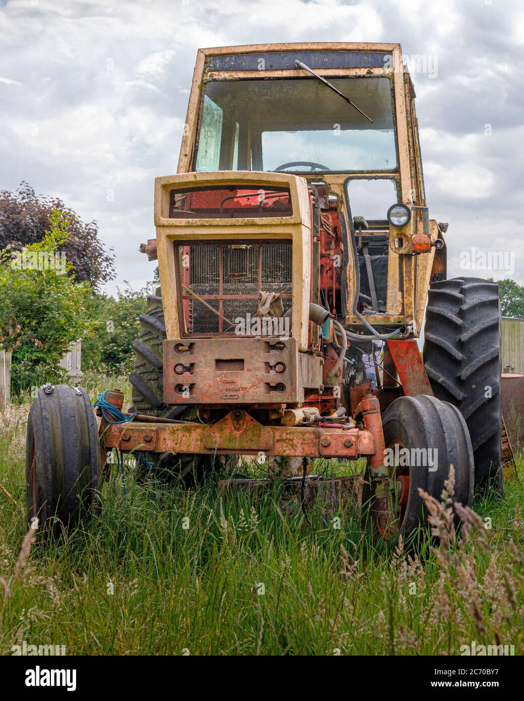 decaying in need or repair american case 970 tractor in field with moody sky Stock Photo