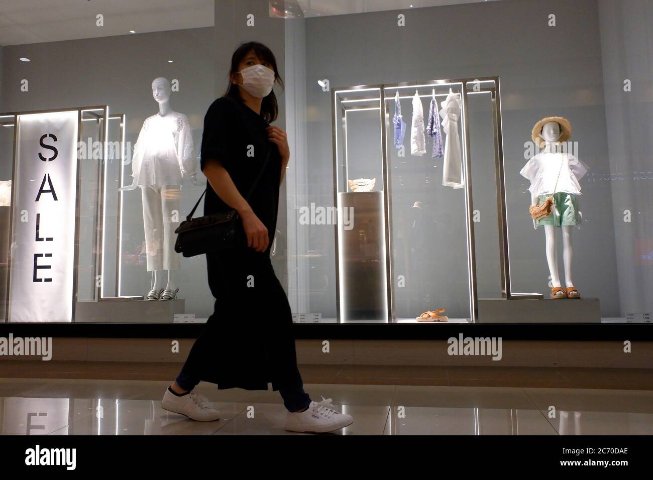 A woman wearing a protective face mask walks past a ZARA store at a shopping district amid the coronavirus (COVID-19) outbreak.Tokyo on Monday reported 119 new coronavirus infections, falling below 200 for the first time in five days, Tokyo Gov. Yuriko Koike said. Stock Photo
