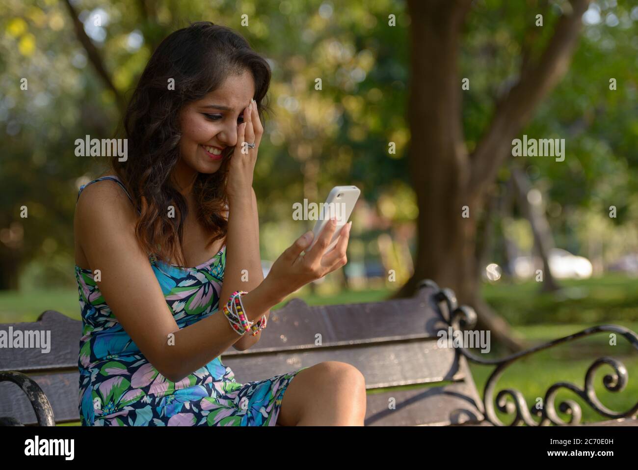 Happy young beautiful Indian woman using phone and getting good news at ...