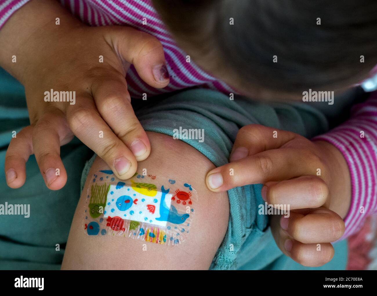 Leipzig, Germany. 11th July, 2020. A child sticks a colourful plaster on its knee (posed picture). Credit: Hendrik Schmidt/dpa-Zentralbild/ZB/dpa/Alamy Live News Stock Photo