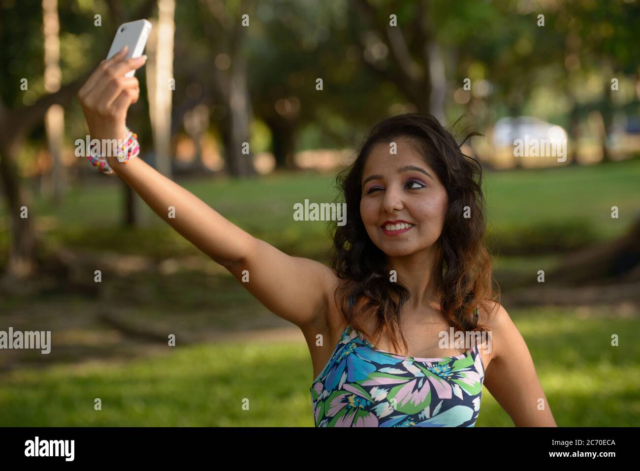 Happy young beautiful Indian woman taking selfie at the park Stock ...