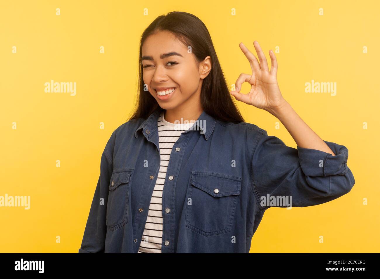 Alright, I agree! Portrait of cheerful smiling girl in denim shirt showing ok hand gesture, approval cool symbol, satisfied with excellent result. ind Stock Photo