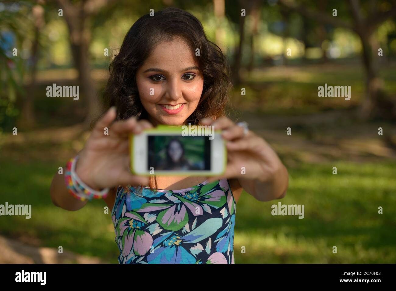 Happy young beautiful Indian woman taking selfie at the park Stock ...