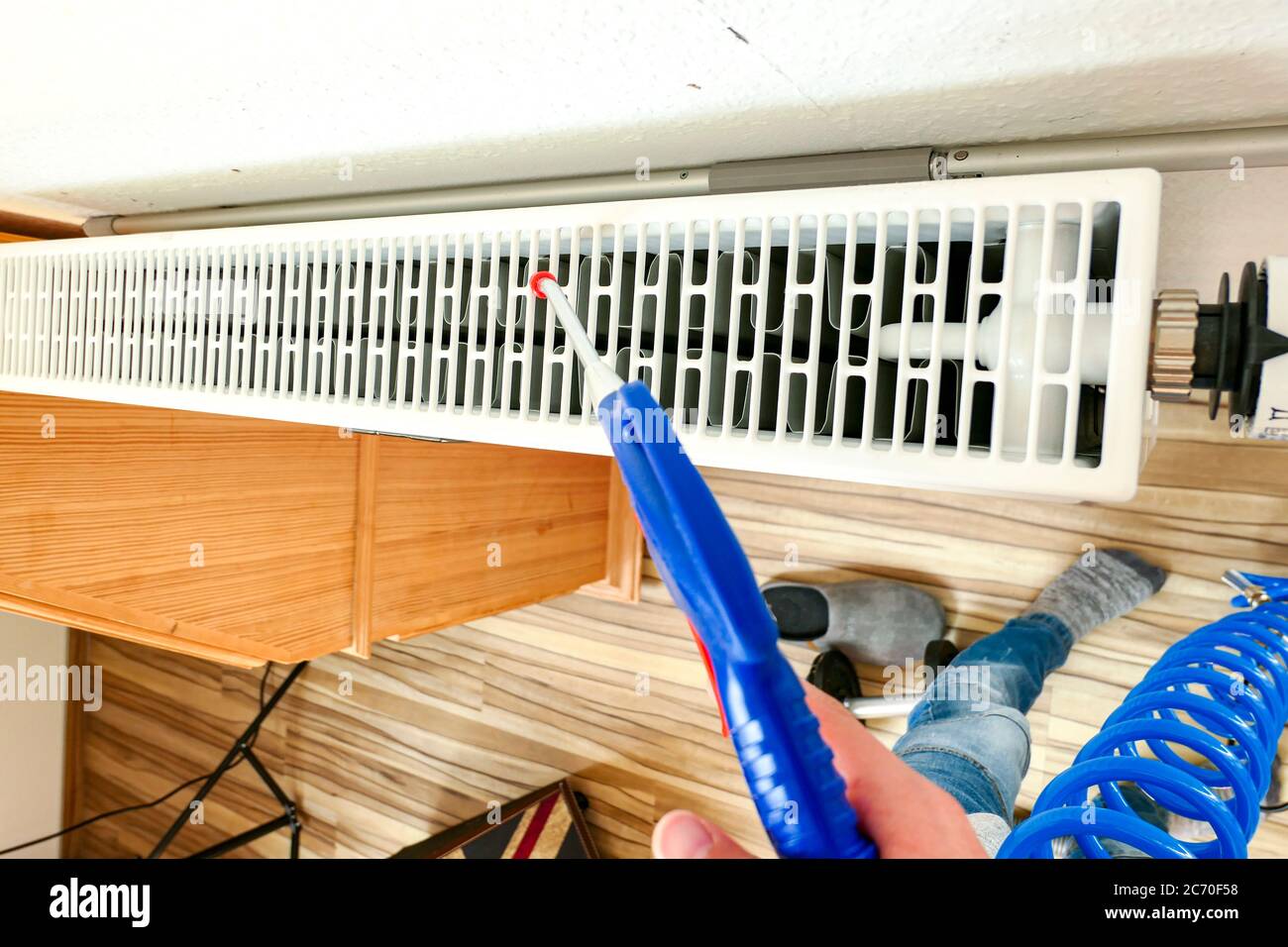 Clean dust from radiators in the room with compressed air Stock Photo