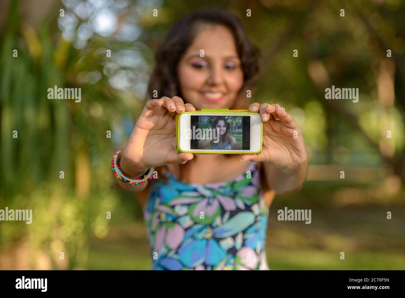 Happy young beautiful Indian woman taking selfie at the park Stock ...
