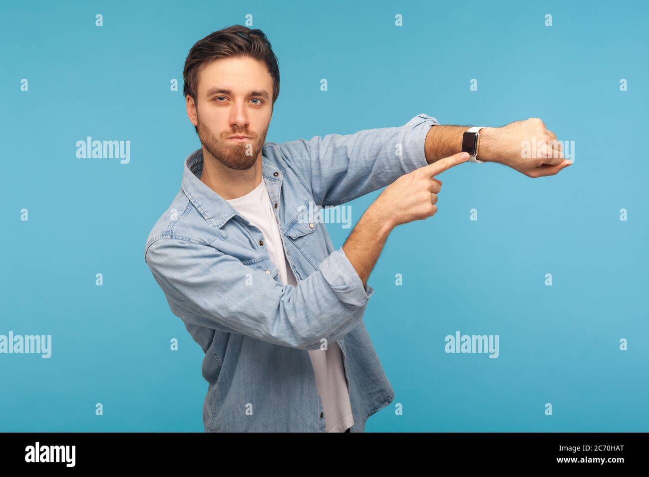 Hurry up! Portrait of impatient angry man in worker denim shirt pointing at wrist watch and expressing dissatisfaction with late time, delayed meeting Stock Photo