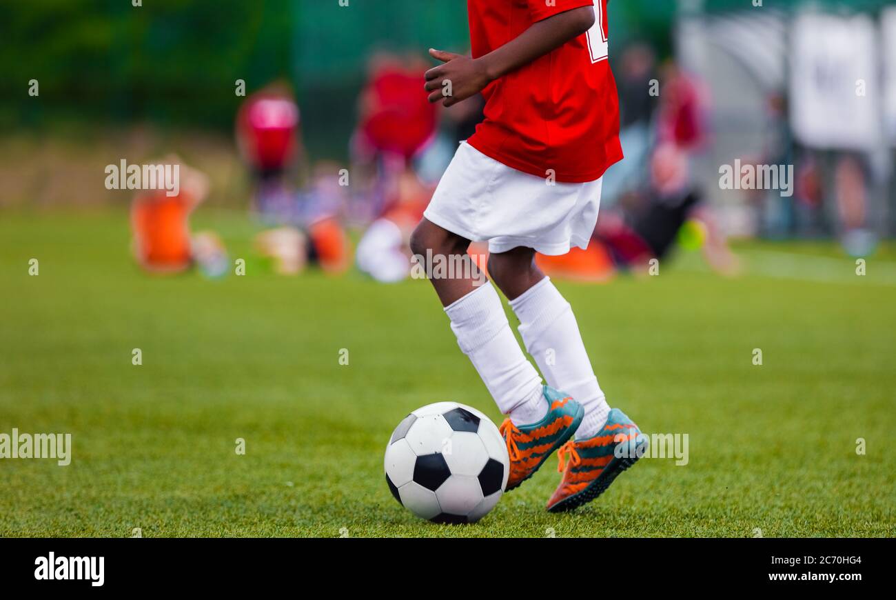 African American Boy in Junior Football Team Leading Ball on Grass