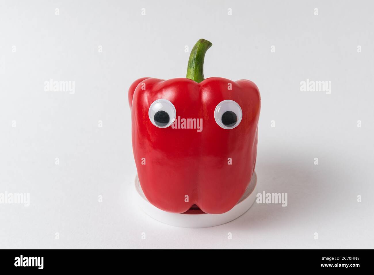 Raw red peppers with Googly eyes on white background. Pepper with funny