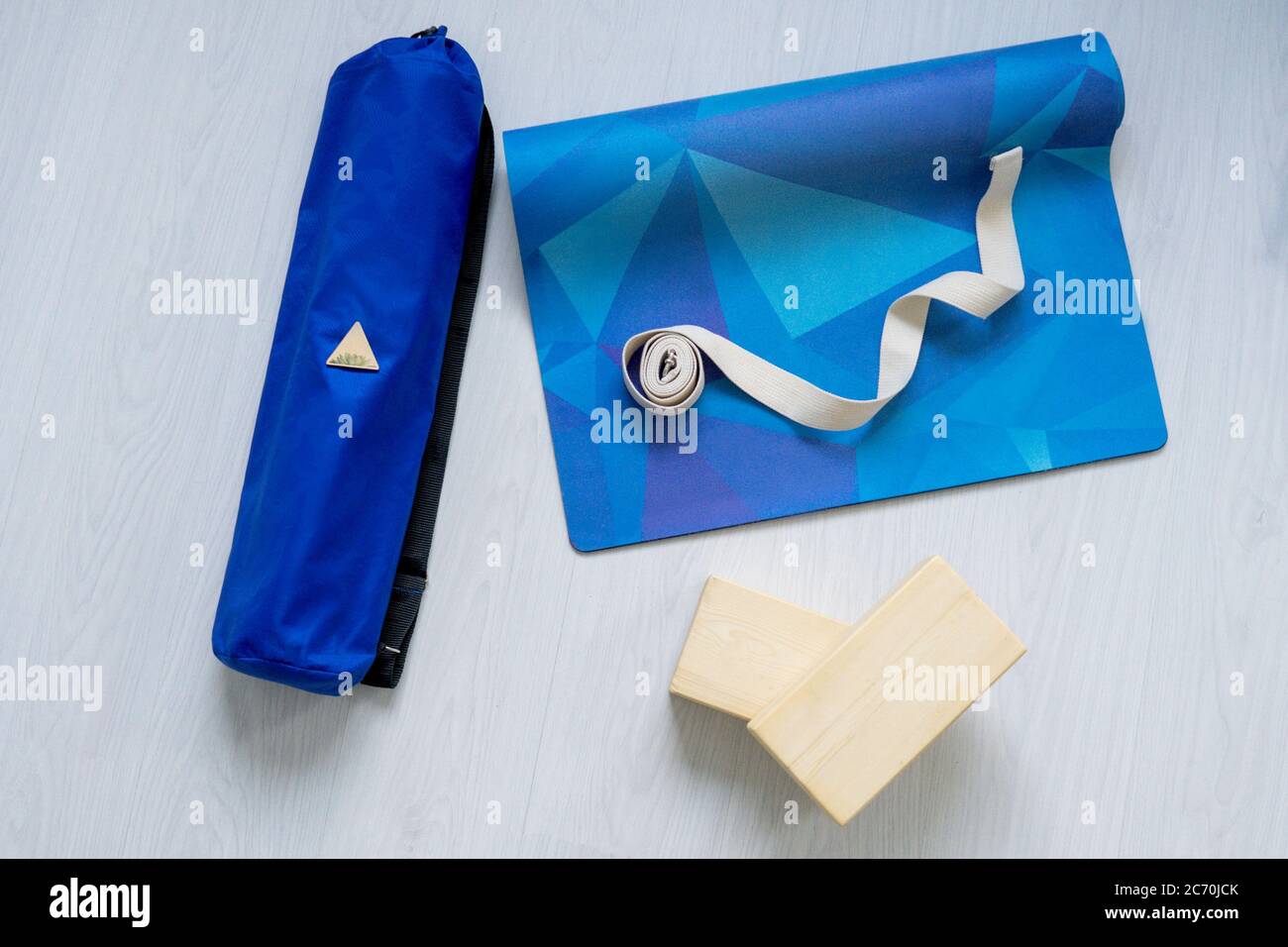 Flat lay from yoga equipment. Blue mat, blocks and belt on light