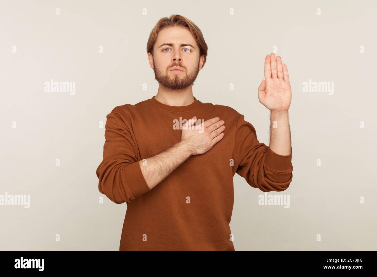 I promise to tell truth! Portrait of honest responsible bearded man in sweatshirt standing raising hand and saying swear, making loyalty oath, pledgin Stock Photo