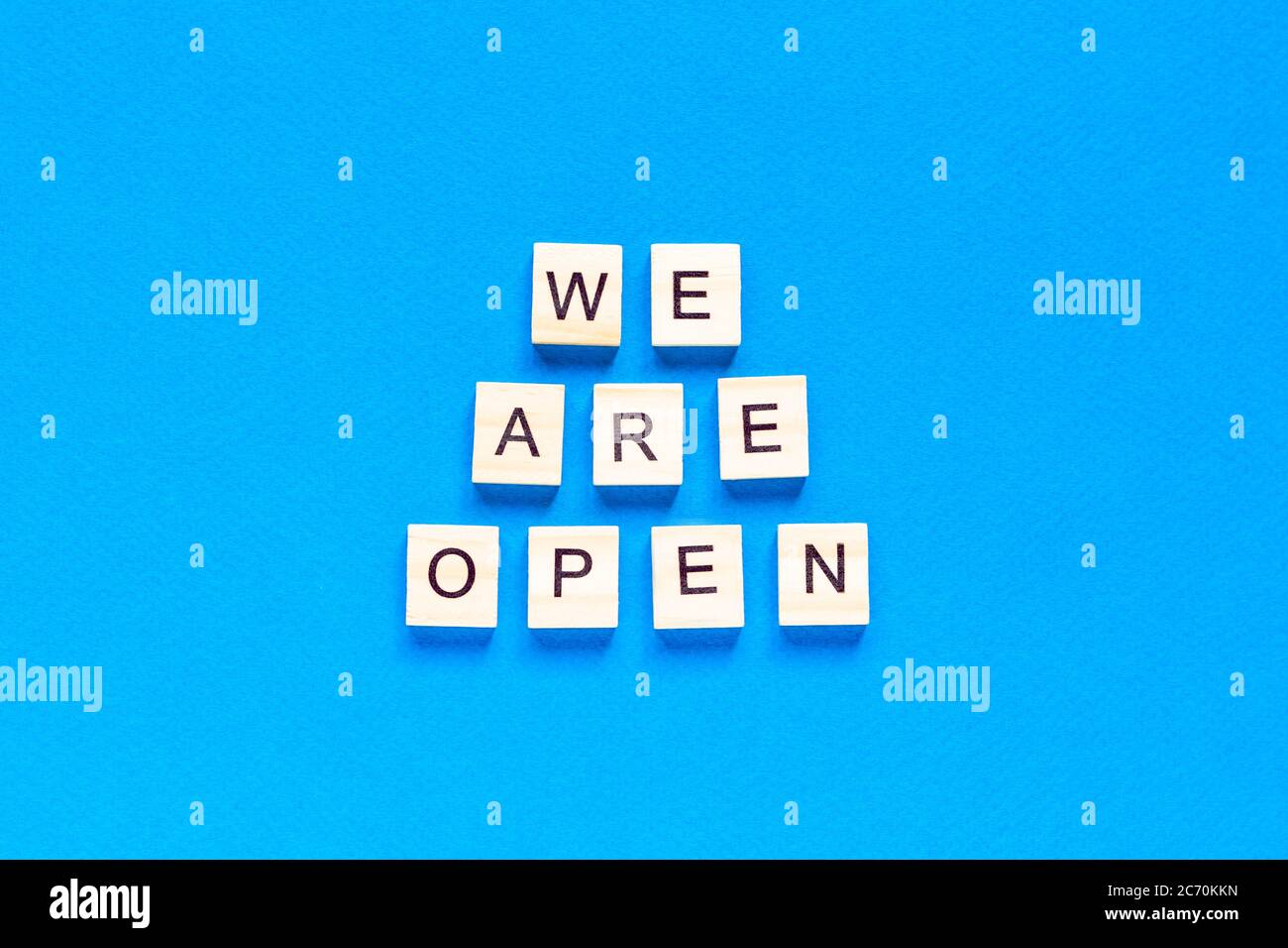 We are open. Wooden cubes with a text message We are open on a blue background. The view from the top. Flat layout. An office, cafe, or store welcomes Stock Photo