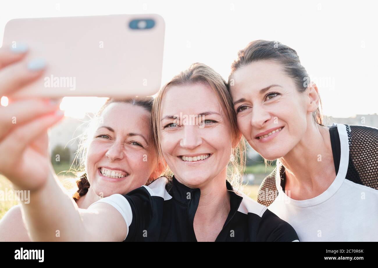 Three young woman friends taking a selfie posing close together smiling ...