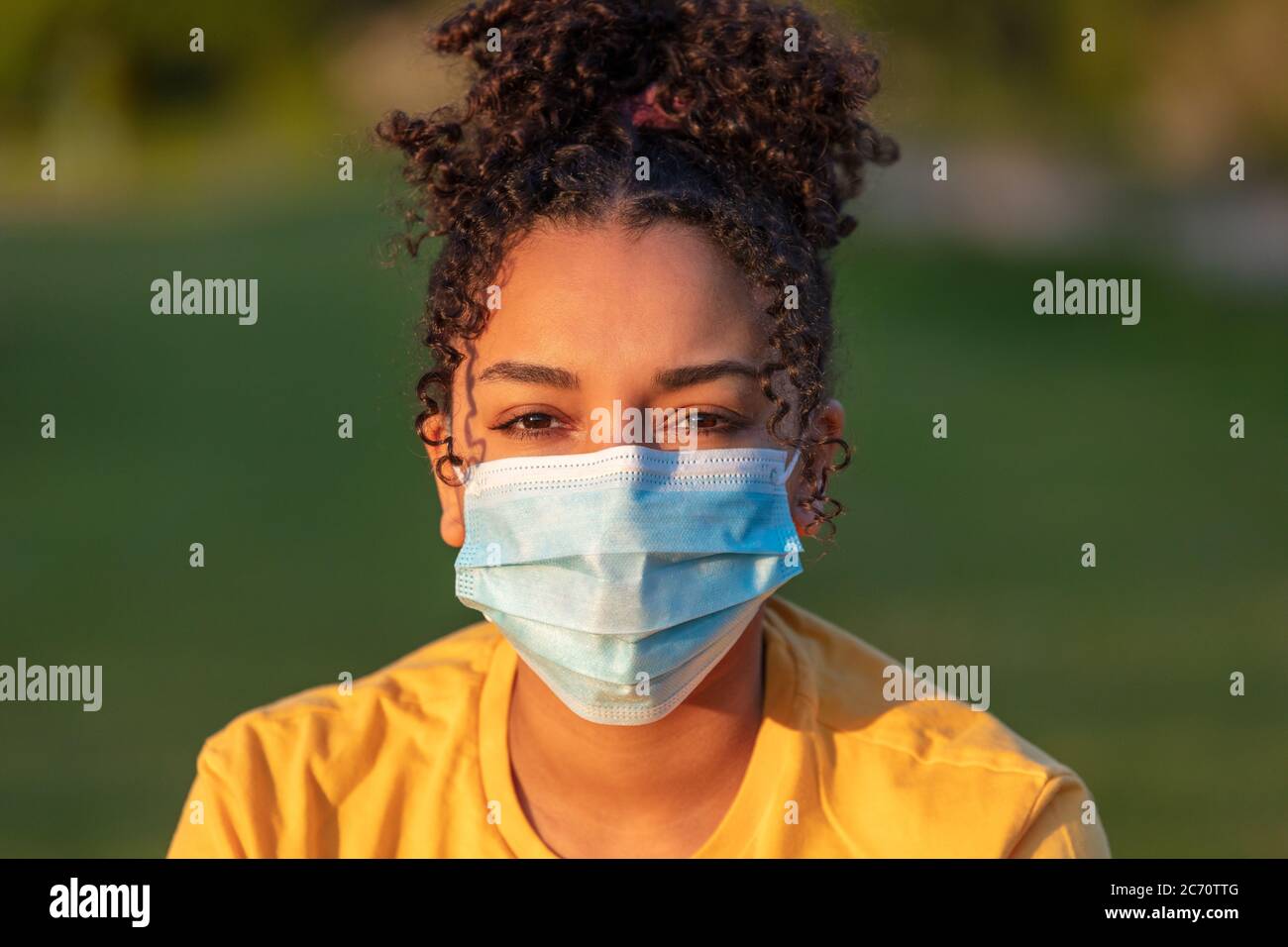 Mixed race African American teenager teen girl young woman wearing a face mask outside during the Coronavirus COVID-19 pandemic Stock Photo