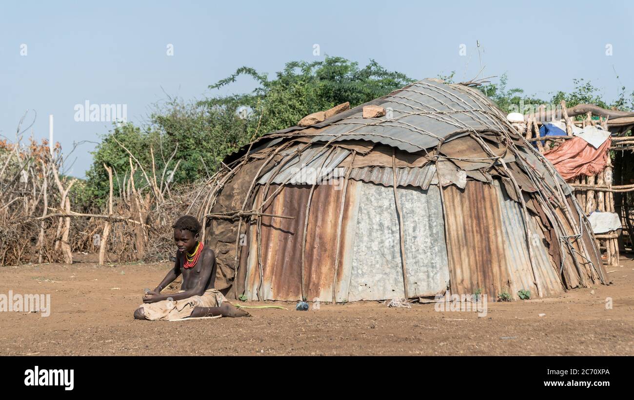 Omorate, Ethiopia - September 2017: Unidentified girl from Dassanech tribe sitting on soil ground , Ethiopia Stock Photo