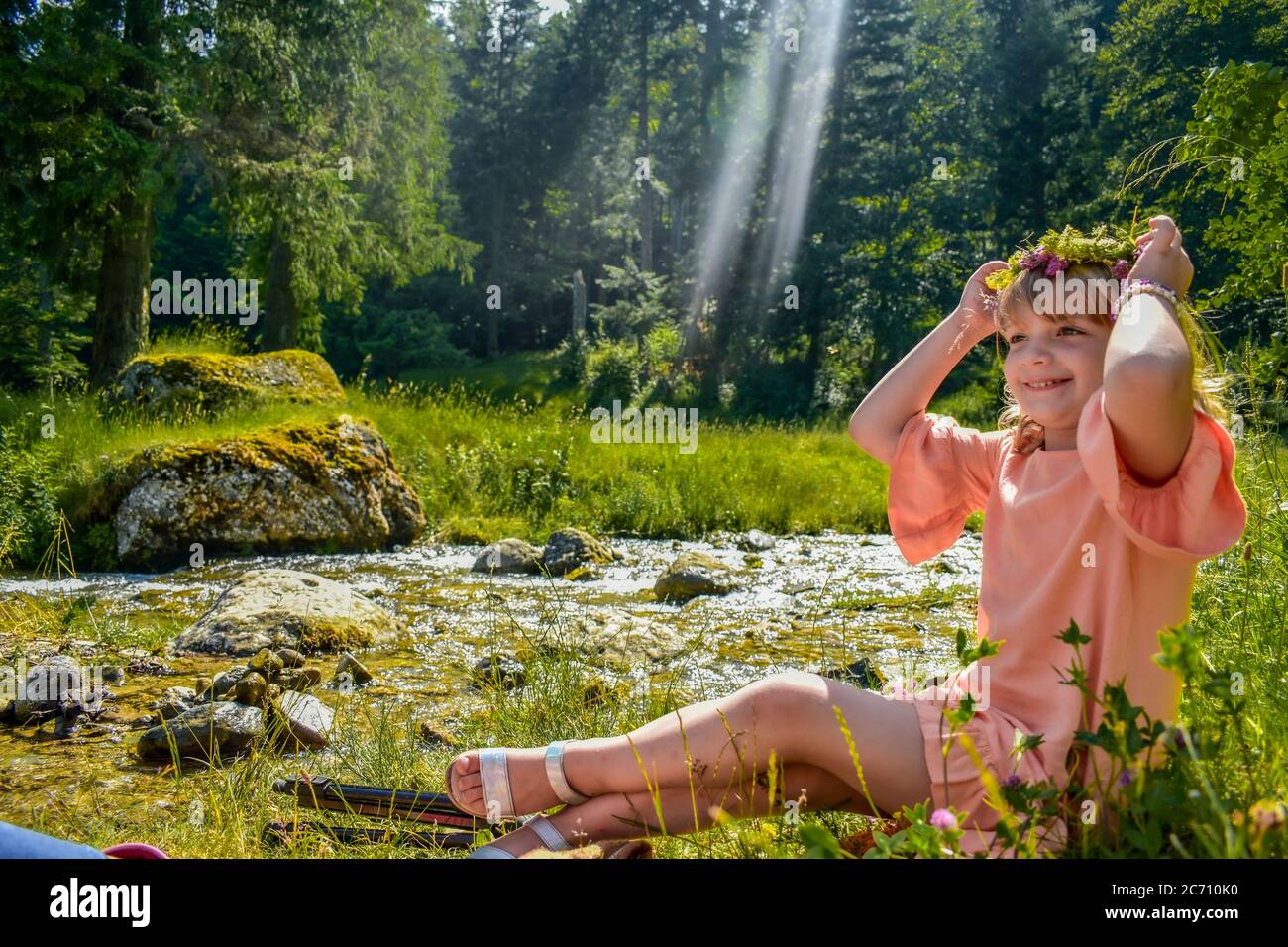 young blonde child with a crown on her head in a forest looking like a fairy Stock Photo