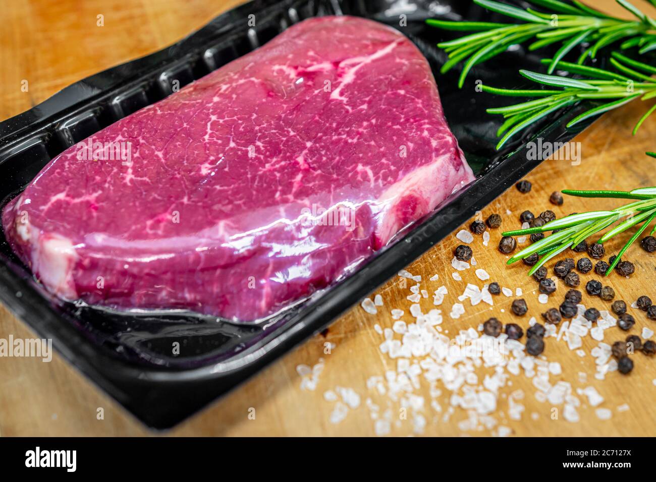 Beef steak in vacuum skin packaging and spices on wooden chopping board Stock Photo