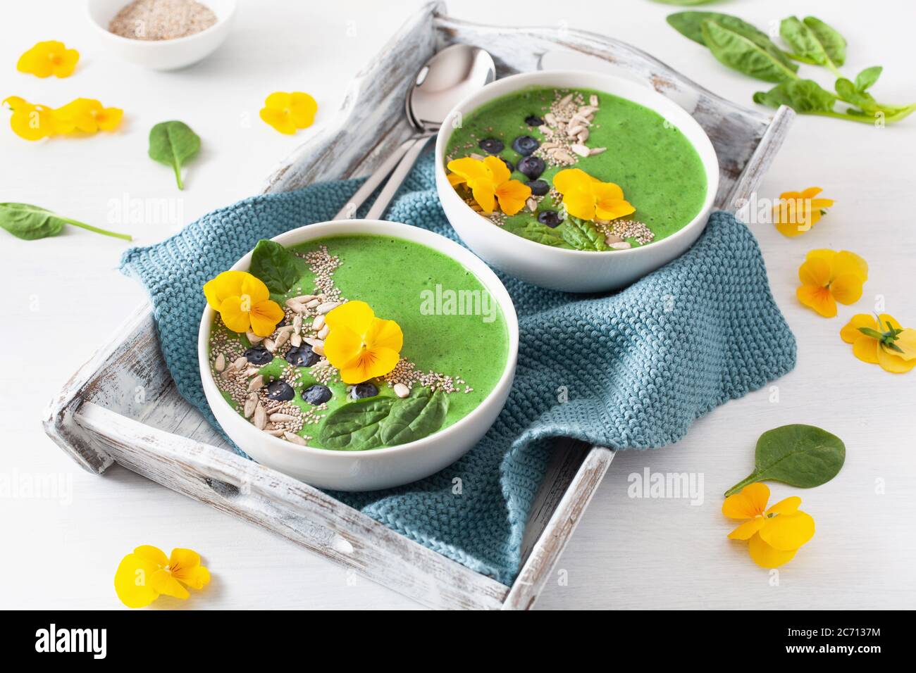 green spinach smoothie bowl with blueberry, chia seed and edible pansy