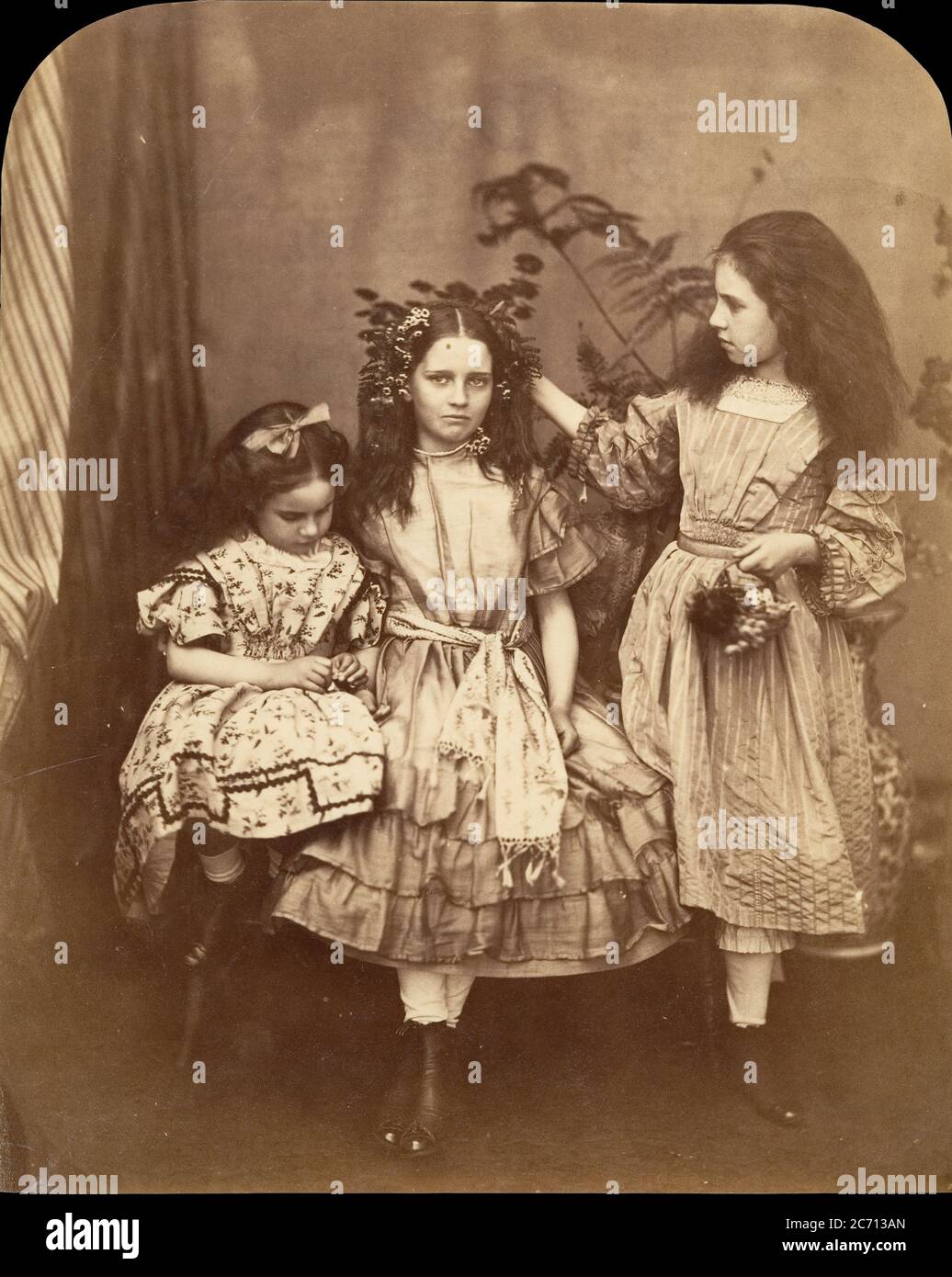 Flora Rankin, Irene MacDonald, and Mary Josephine MacDonald at Elm Lodge, July 1863. Irene and Mary MacDonald were the children of Scottish novelist and poet George MacDonald. Carroll was a friend of the family, and the children affectionately called him &quot;Uncle.&quot; This photograph, which includes the children's friend Flo Rankin standing in the middle, was produced during the photographer's stay at Elm Lodge in Hampstead the week of July 25, 1863. Stock Photo