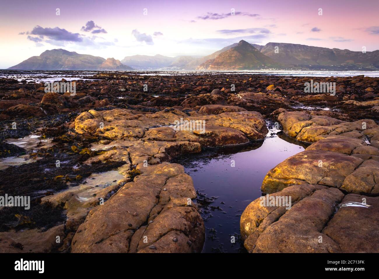 View of a cloudy sunset over False Bay from Kommetjie Beach, with beautiful rocks in the breaking waves , Cape Town, South Africa Stock Photo