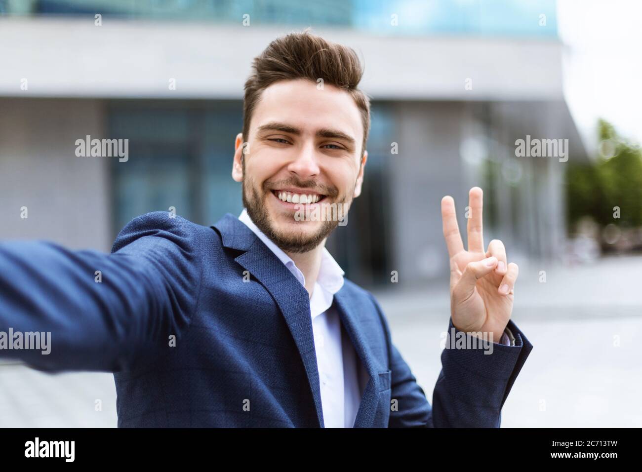 Smiling young businessman using video chat or taking selfie at city center Stock Photo