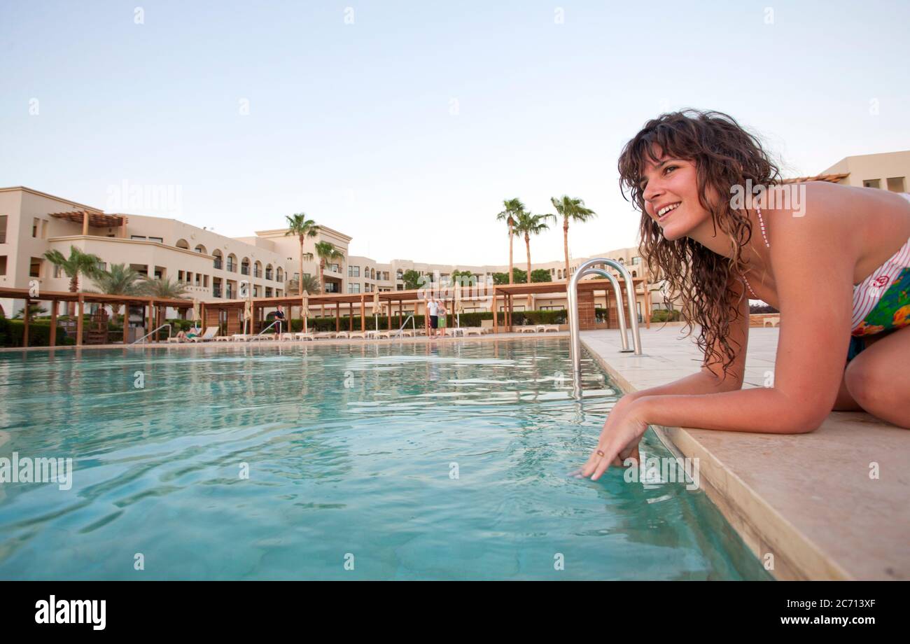Jordan, Aqaba, Tala Bay Luxury Beach Resort young woman by the swimming pool - Model release available Stock Photo