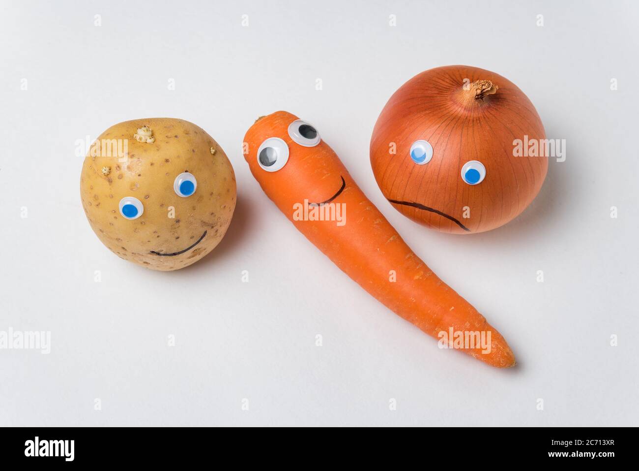 Potatoes, carrots and onion with Googly eyes and on white background