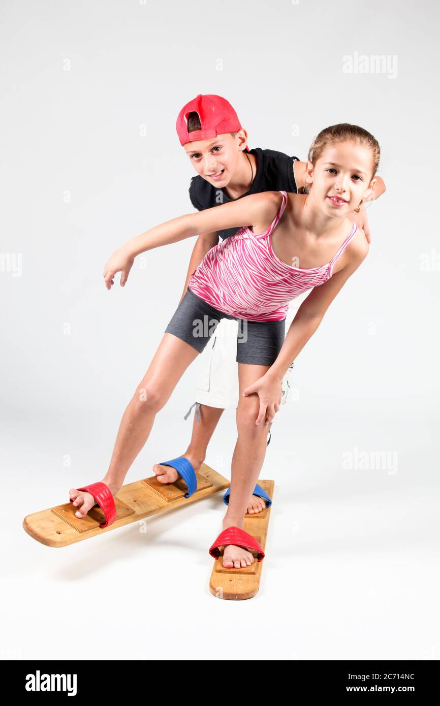 Indoor playground  2 children aged 8-12 attempt to walk together on wooden walking skies On white Background Stock Photo