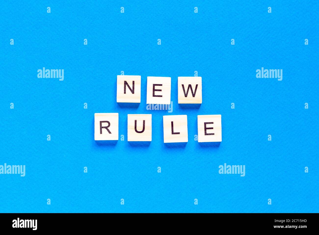 The NEW RULE is written in wooden letters on a blue background. New concept. Business, law, rules, update. tflat layout. op view. Stock Photo