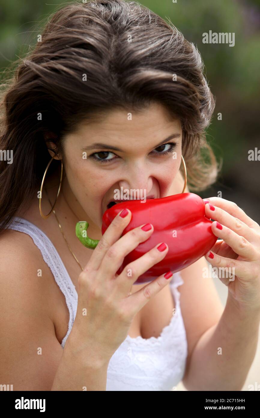 Young woman eats a whole red bell pepper Stock Photo