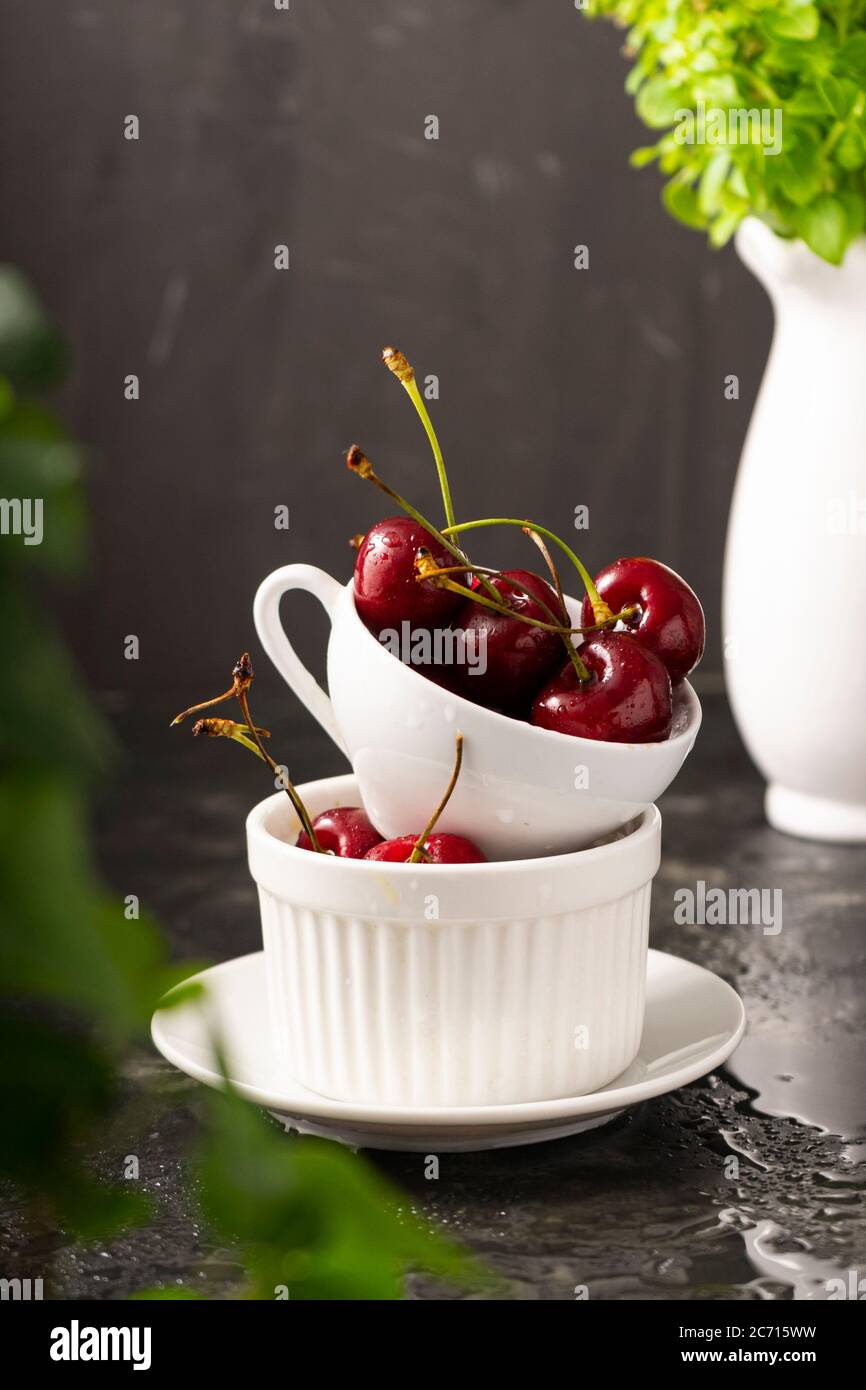 Selective focus, ripe cherries with water drops in a ceramic white Cup ...