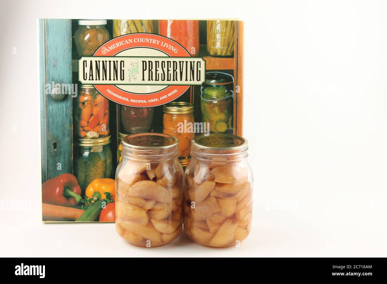 Canning and preserving american country living cook book with two glass jars of preserved apples isolated on a white background, copy space Stock Photo