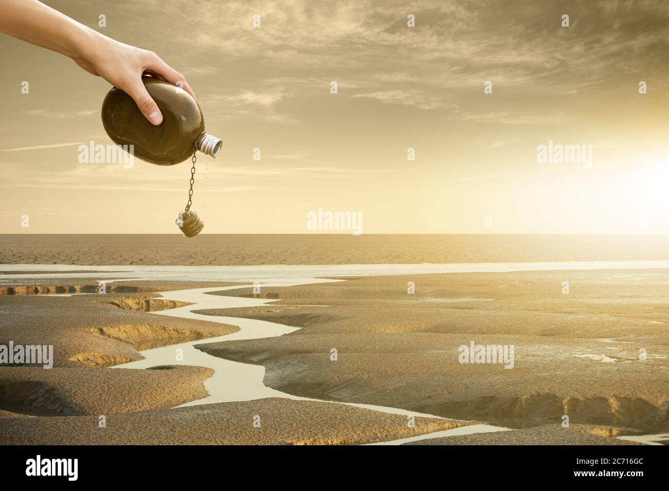 A man pours water from a flask on a dried river. Drought and water scarcity caused by global warming Stock Photo