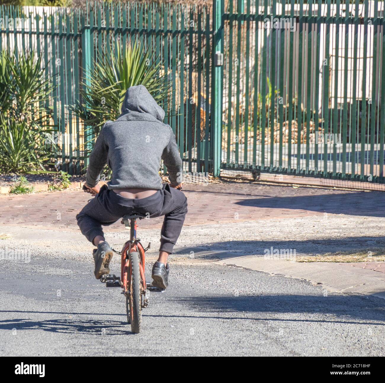 Alberton, South Africa - unidentified black youth rides a small bicycle in a public street image in landscape format Stock Photo