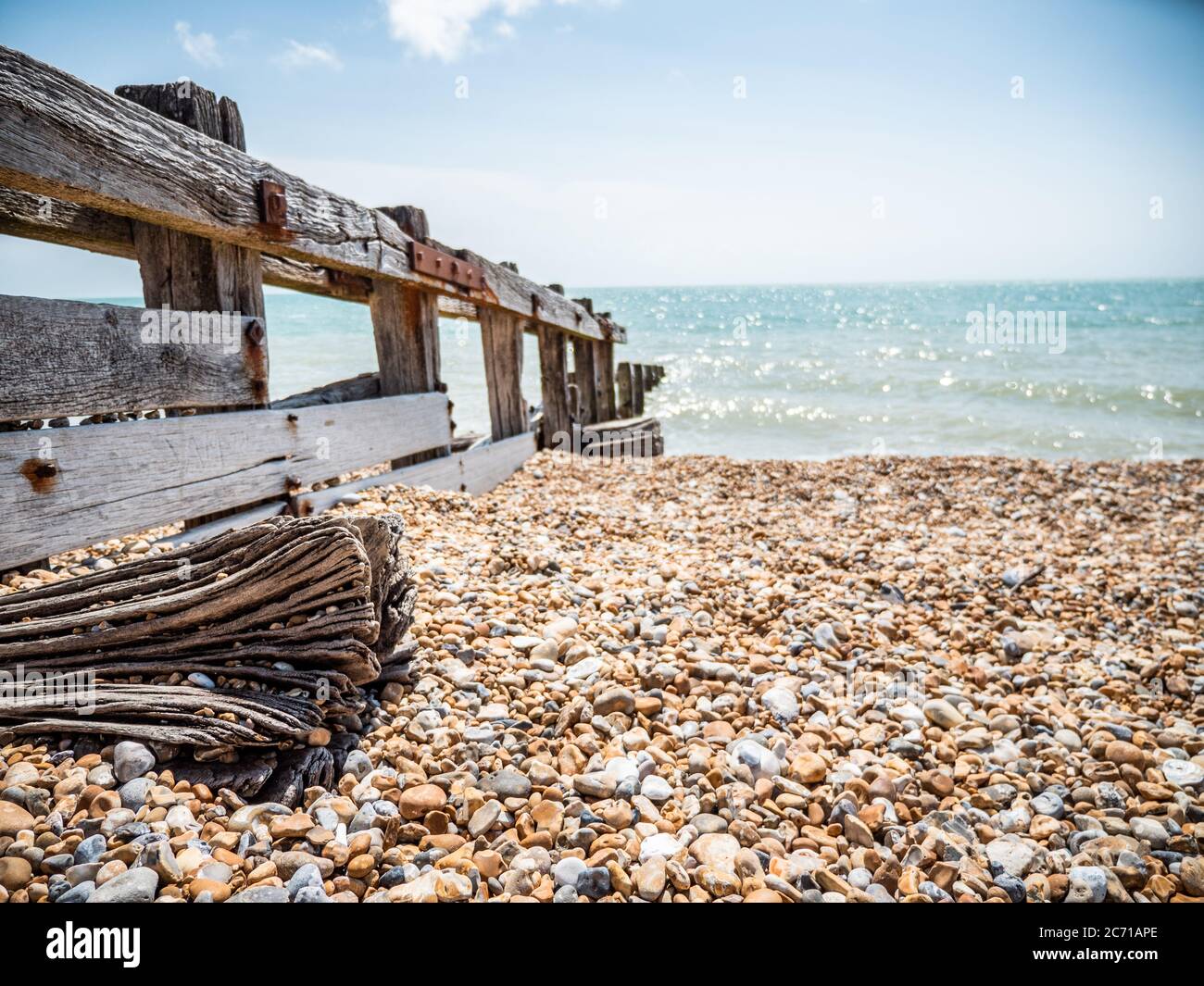Wave breaker, Sussex, England. An old wavebreaker on a pebbled beach leading into the sea on the south coast of England. Stock Photo
