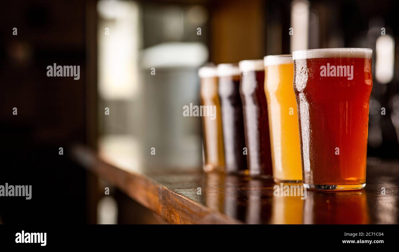 Degustation of beer. Many different types of craft drink in big glasses on table in pub interior Stock Photo