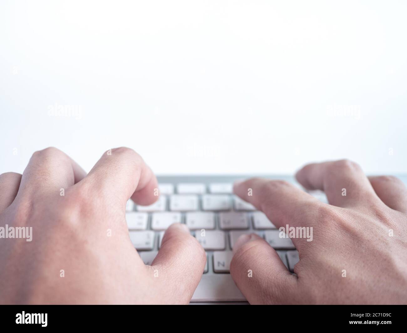 Close-up hands typing on remote control wireless computer keyboard isolated on a white background with copy space. Stock Photo